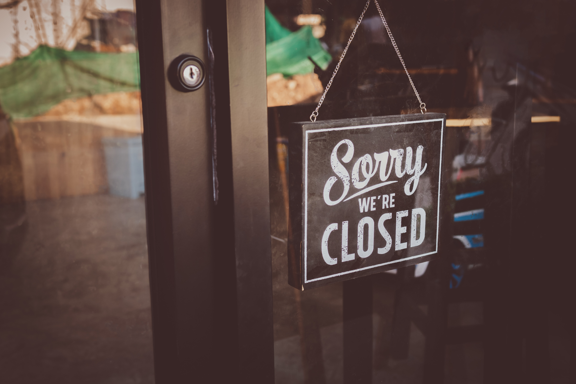 Label 'Sorry we're closed' notice sign wood board hanging on door front coffee shop.